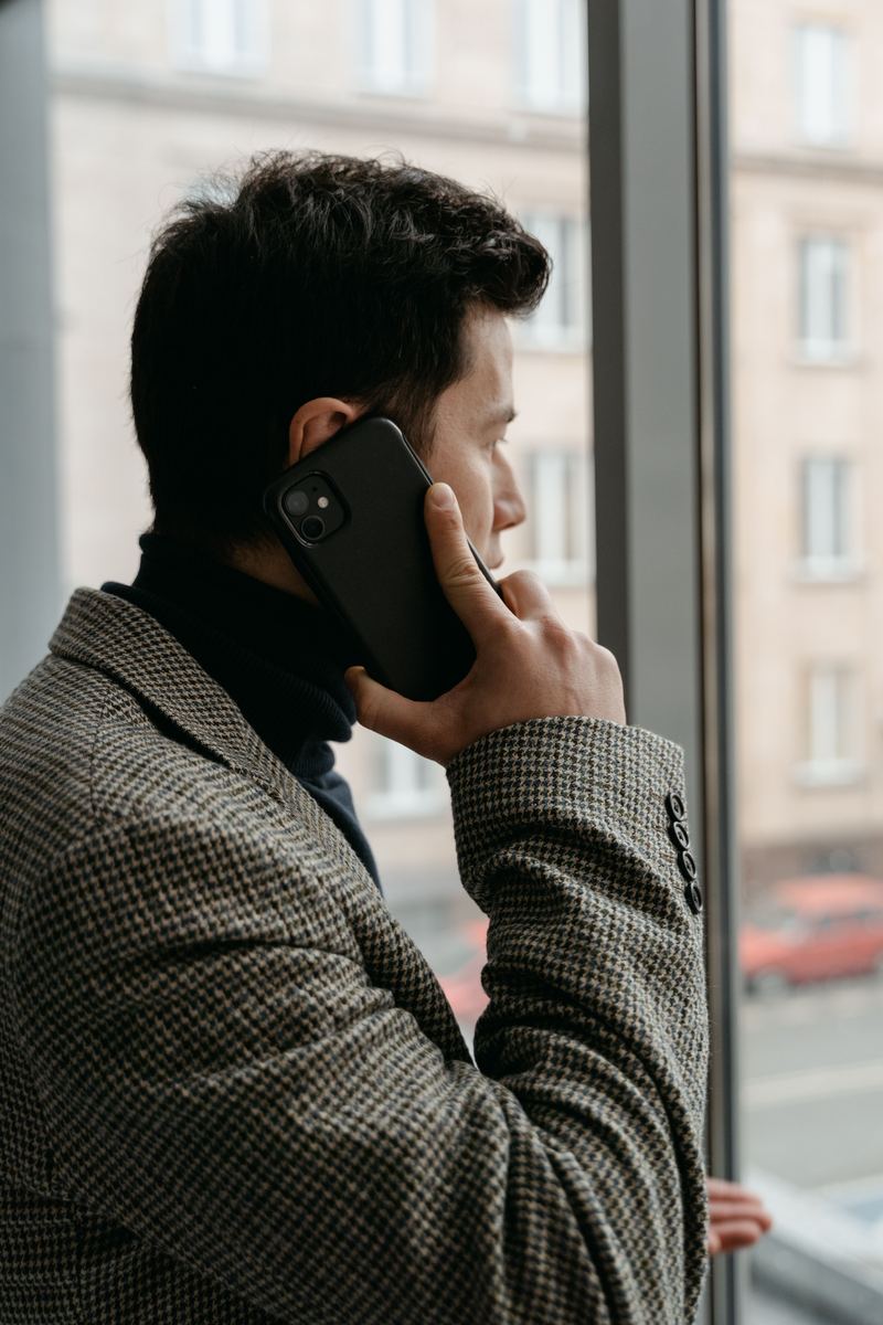 Man checking phone outside office window, local business owner
